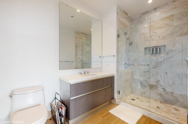 bathroom featuring toilet, vanity, wood-type flooring, and a shower with shower door