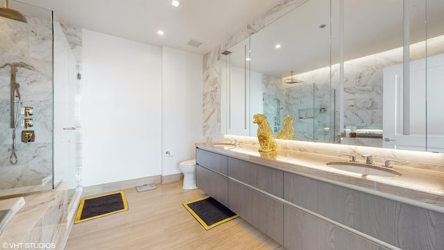 bathroom featuring toilet, vanity, and a shower with door