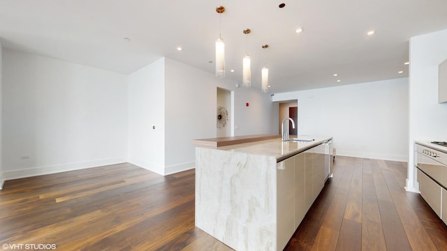 kitchen with pendant lighting, sink, a kitchen island with sink, dark wood-type flooring, and white cabinets