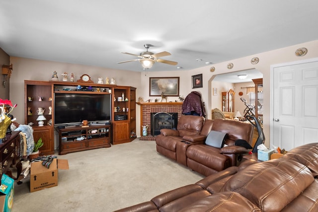 carpeted living room with ceiling fan and a brick fireplace