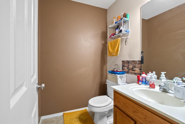 bathroom with toilet, vanity, and tasteful backsplash