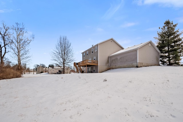 snow covered back of property featuring a deck