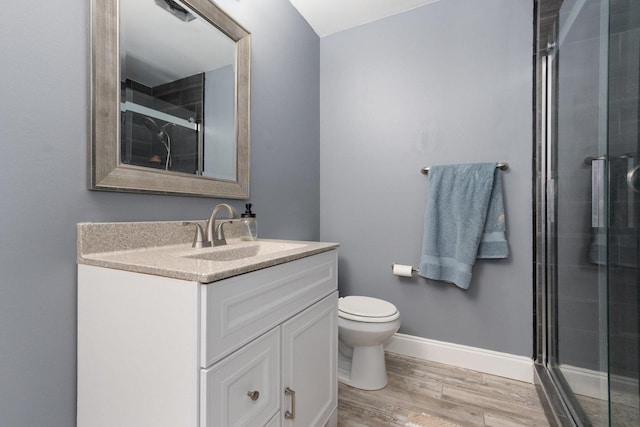 bathroom featuring vanity, wood-type flooring, a shower with door, and toilet