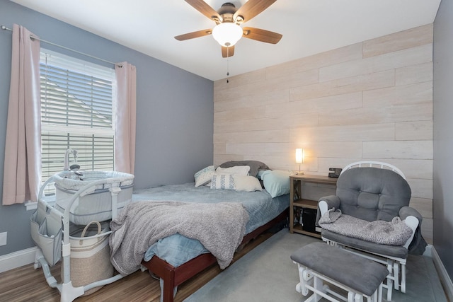 bedroom featuring ceiling fan and wooden walls