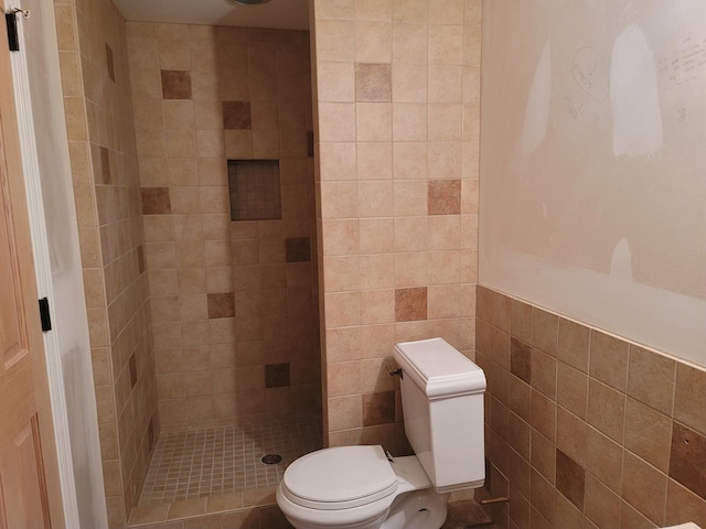 bathroom featuring toilet, tile walls, and a tile shower