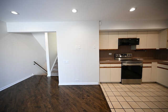 kitchen with stainless steel electric range oven, backsplash, and light hardwood / wood-style flooring