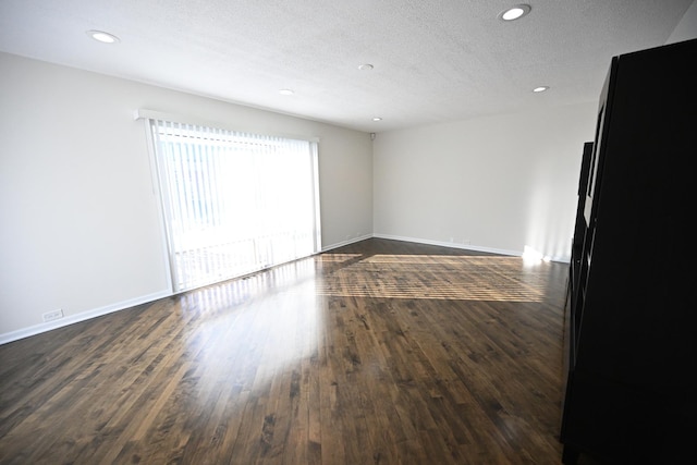 empty room featuring a textured ceiling and dark hardwood / wood-style floors