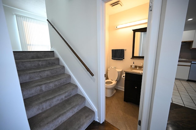 staircase featuring sink and hardwood / wood-style flooring