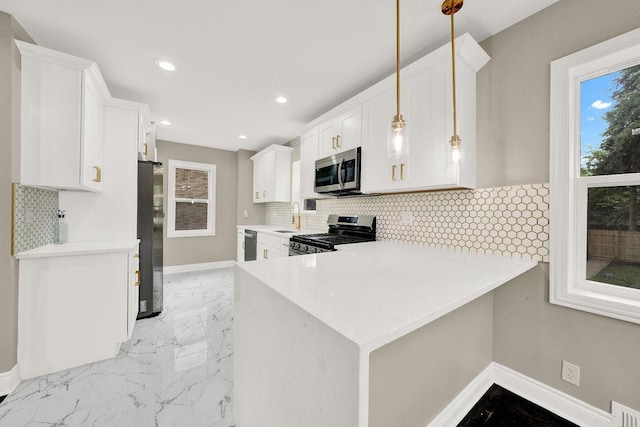 kitchen with white cabinets, appliances with stainless steel finishes, decorative light fixtures, tasteful backsplash, and kitchen peninsula