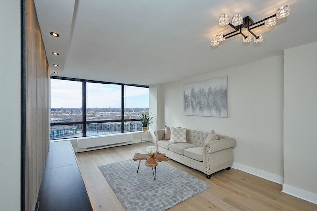 living room with baseboard heating, a chandelier, and light hardwood / wood-style flooring