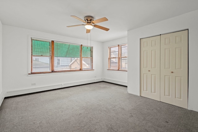 unfurnished bedroom with ceiling fan, light colored carpet, a baseboard heating unit, and a closet