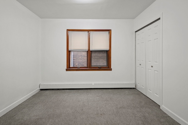 unfurnished bedroom featuring a baseboard heating unit, a closet, and carpet floors