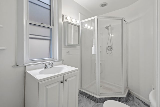 bathroom featuring a shower with shower door, vanity, and toilet