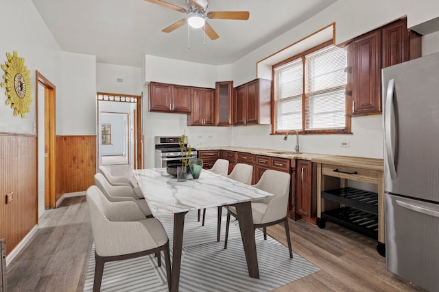 kitchen with appliances with stainless steel finishes, sink, wooden walls, and light hardwood / wood-style floors