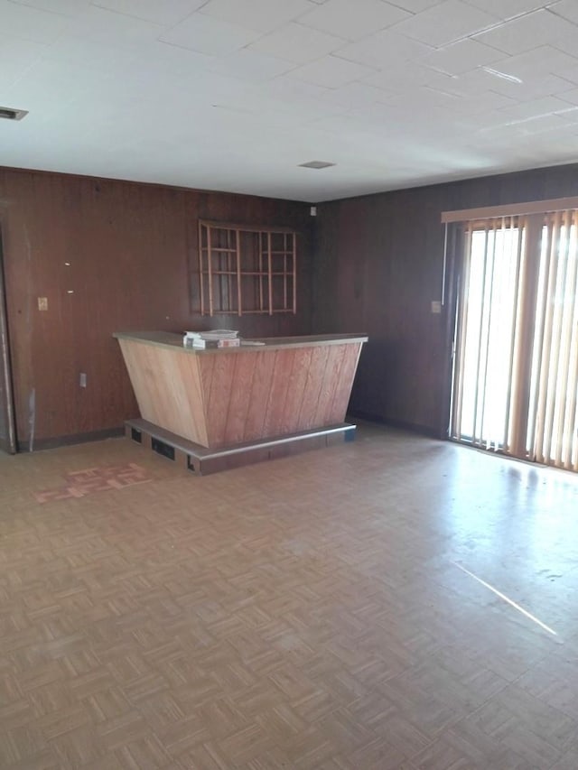 interior space featuring parquet floors, kitchen peninsula, and wood walls