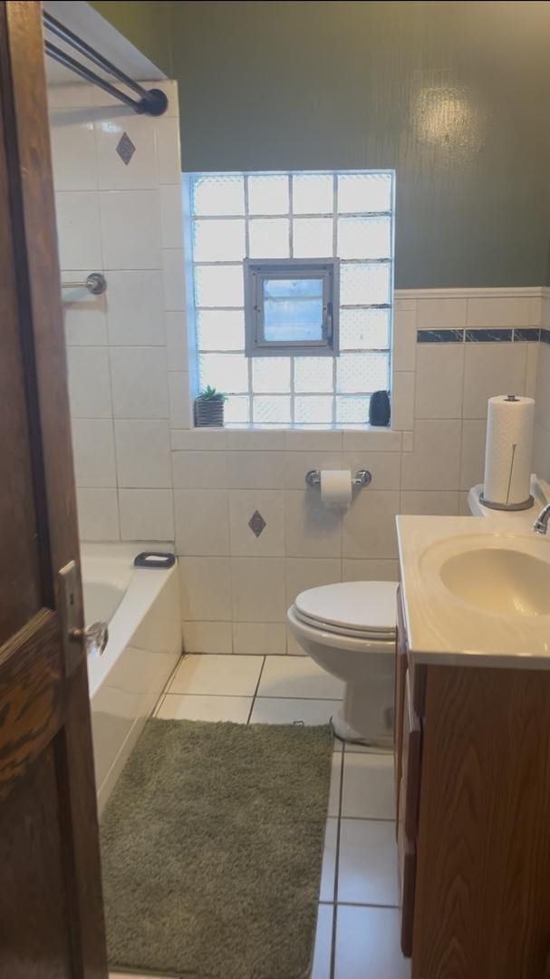 bathroom featuring toilet, tile walls, vanity, tile patterned flooring, and a washtub