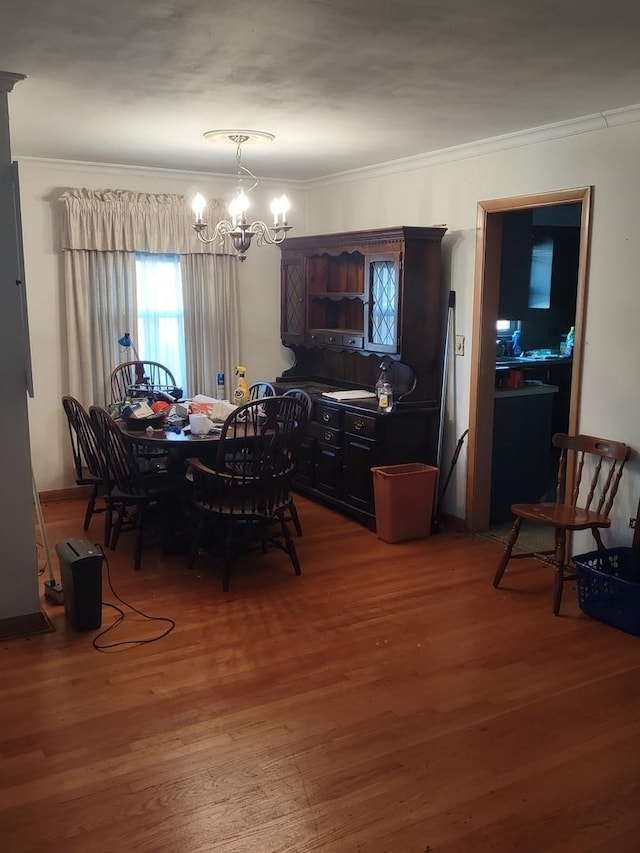 dining room featuring wood-type flooring, crown molding, and a notable chandelier