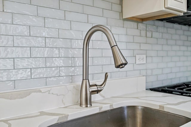 interior details featuring decorative backsplash, sink, and light stone counters