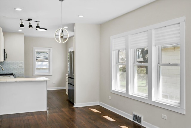 kitchen with pendant lighting, decorative backsplash, white cabinetry, track lighting, and dark hardwood / wood-style flooring