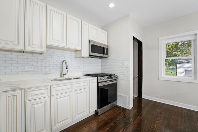 kitchen with sink, white cabinetry, light stone countertops, stainless steel appliances, and dark hardwood / wood-style flooring