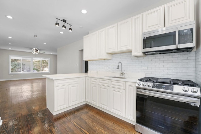 kitchen with white cabinets, kitchen peninsula, appliances with stainless steel finishes, and sink