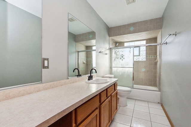 full bathroom with combined bath / shower with glass door, vanity, tile patterned flooring, and toilet