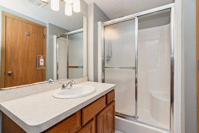 bathroom featuring a shower with door and vanity