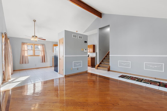 unfurnished living room with beam ceiling, ceiling fan, light tile patterned flooring, and high vaulted ceiling