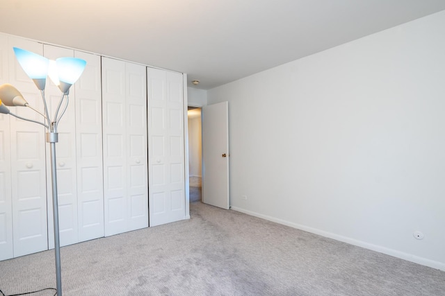 unfurnished bedroom featuring light carpet and a closet