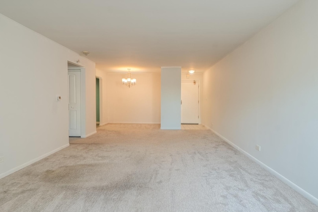 carpeted spare room with a notable chandelier