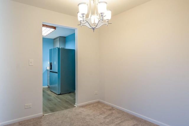 empty room featuring a chandelier and light carpet