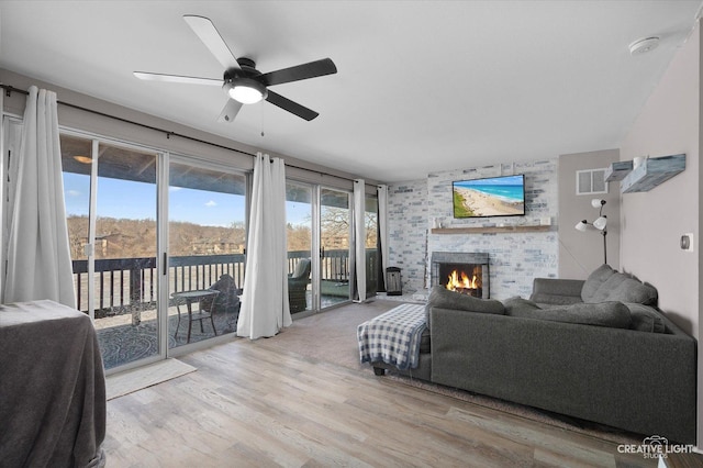 living room with ceiling fan, light wood-type flooring, and a fireplace