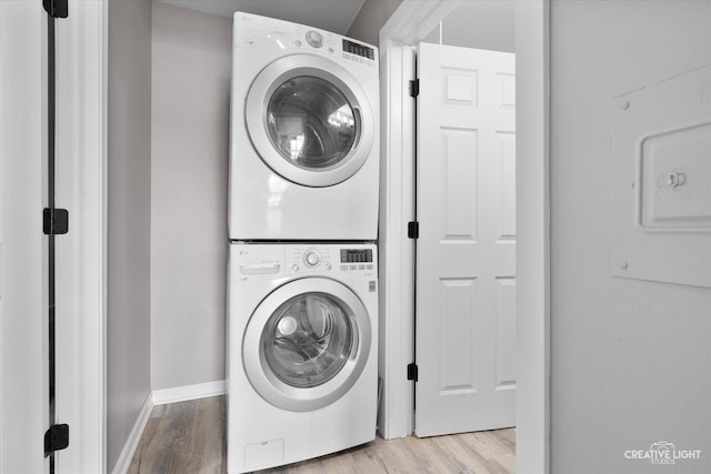 clothes washing area with stacked washing maching and dryer and light wood-type flooring