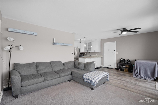 living room with ceiling fan, sink, and light hardwood / wood-style flooring