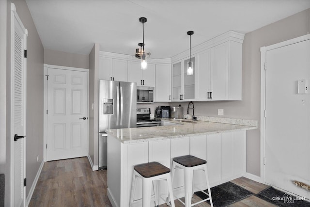 kitchen with pendant lighting, kitchen peninsula, sink, stainless steel appliances, and white cabinets