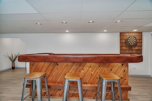 bar with a drop ceiling and light hardwood / wood-style flooring