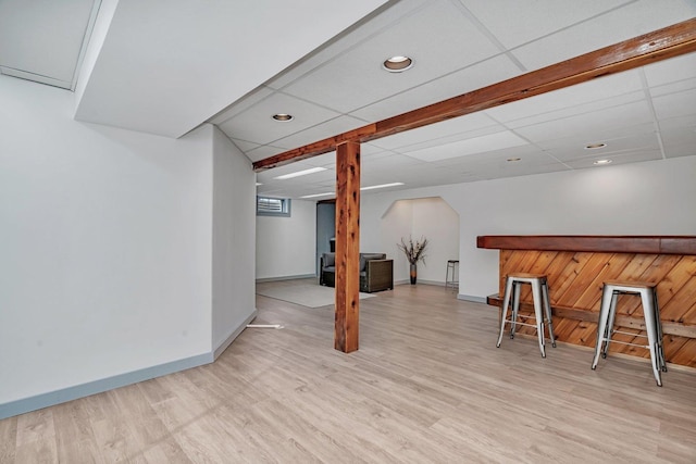 basement featuring a paneled ceiling and light hardwood / wood-style floors