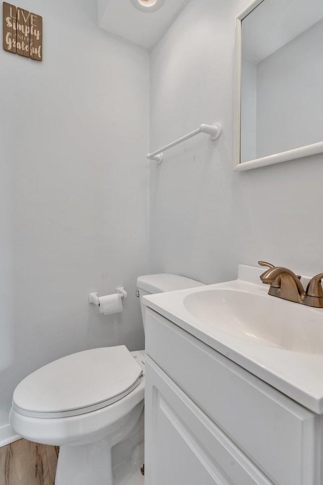 bathroom featuring wood-type flooring, toilet, and vanity