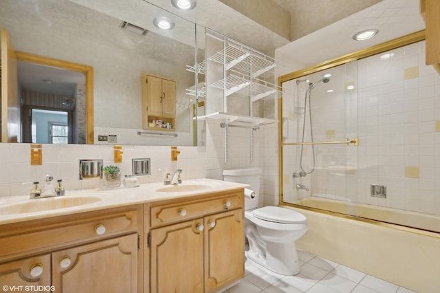 full bathroom with bath / shower combo with glass door, tile walls, tile patterned flooring, vanity, and toilet