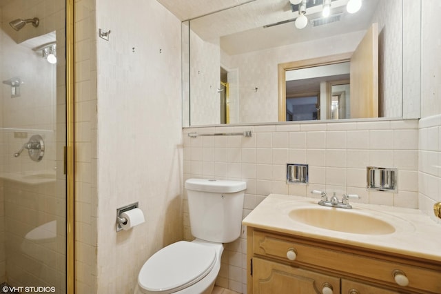 bathroom featuring a shower with door, tile walls, vanity, decorative backsplash, and toilet