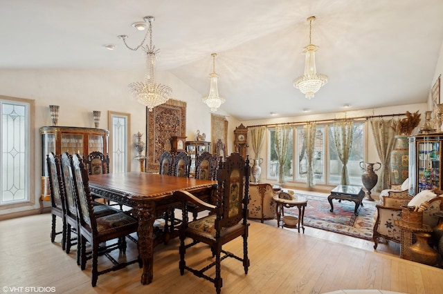 dining space with vaulted ceiling, an inviting chandelier, and light wood-type flooring