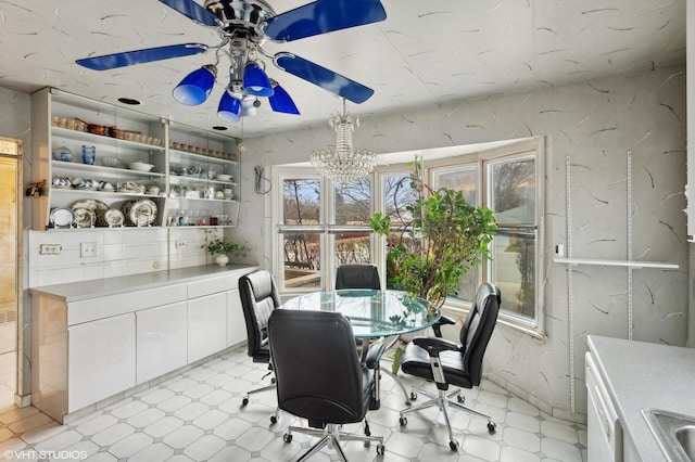 dining space featuring sink and ceiling fan with notable chandelier