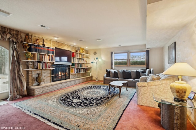 living room featuring a brick fireplace, built in shelves, and carpet