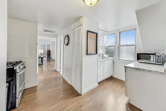 kitchen featuring sink, white cabinetry, light hardwood / wood-style flooring, and stainless steel appliances