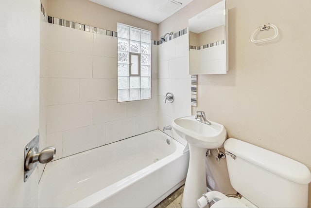 bathroom with tiled shower / bath combo and toilet