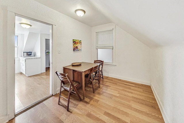 dining space with vaulted ceiling and light hardwood / wood-style flooring