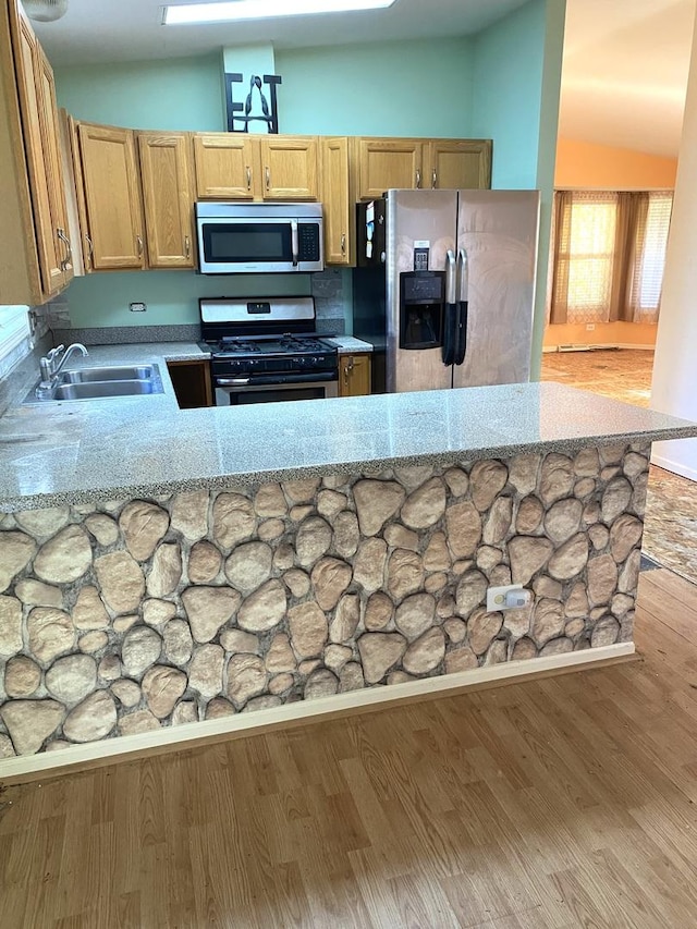 kitchen featuring light stone counters, sink, kitchen peninsula, and stainless steel appliances