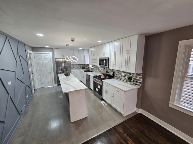 kitchen featuring pendant lighting, white cabinets, stainless steel appliances, and a kitchen island