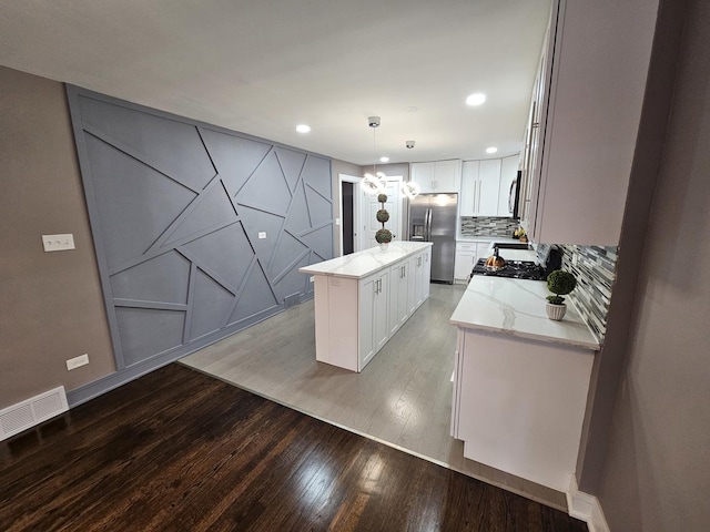 kitchen with white cabinetry, appliances with stainless steel finishes, backsplash, hanging light fixtures, and a center island