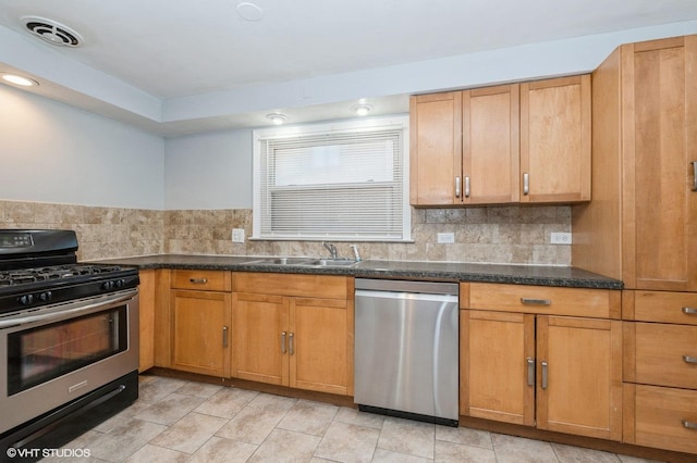 kitchen featuring decorative backsplash, sink, appliances with stainless steel finishes, and dark stone countertops